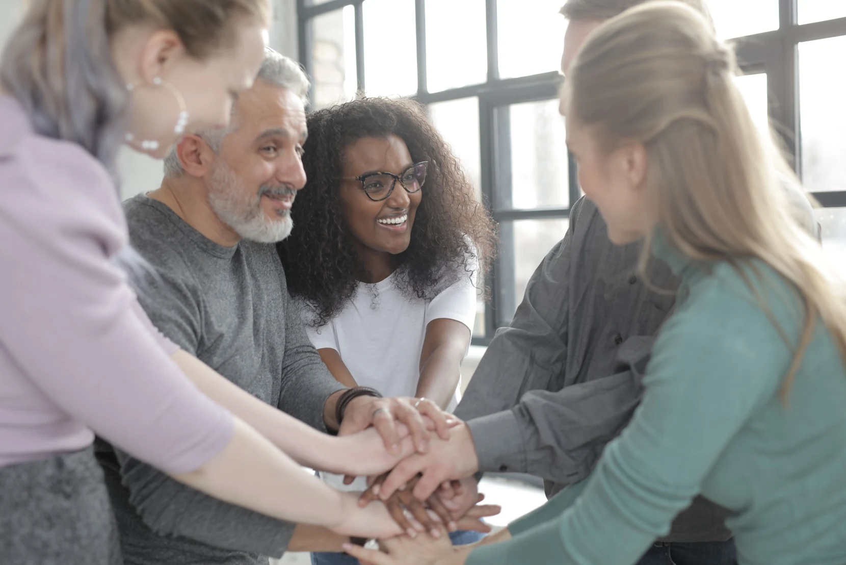 A diverse group joining hands in a supportive group coaching setting